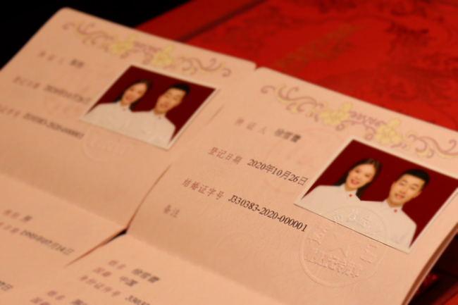 徐小姐和陈先生从颁证员手中接过了结婚证字号为“J330383-2020-000001”的龙港市第一本结婚证